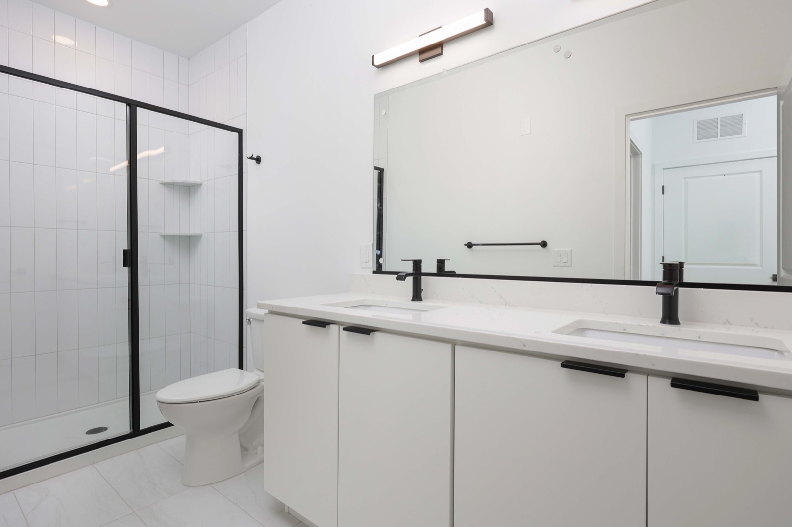 Primary bathroom with double vanity and walk-in shower in a 1BR at The Arthur Carteret